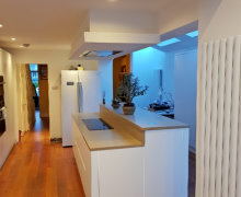 White handleless kitchen with oatmeal quartz worktops and ceiling extractor