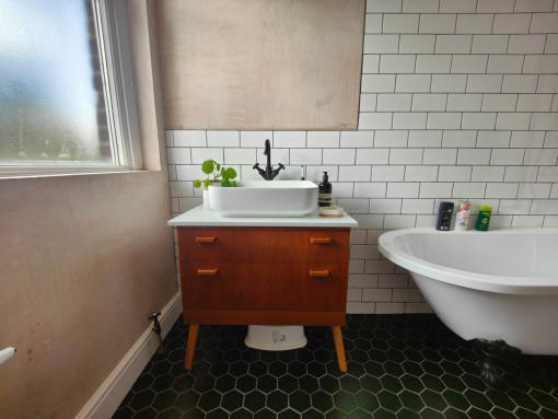 white metro wall tiles, black hexagon floor tiles, victorian style free standing bath and a custom built vanity unit with basin